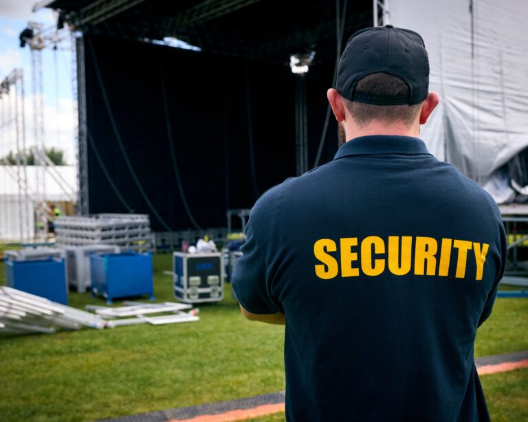 Rear View Of Security Team At Outdoor Stage For Music Festival Or Concert